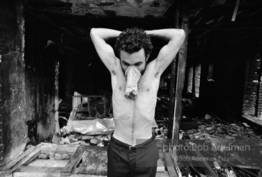 Glue sniffer showing off his biceps in front of a burnt out store. South Bronx, 1978.