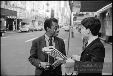 Outside the ANTA Washington Square Theater, James Baldwin signs his autograph for a young fan. New York City, 1964.