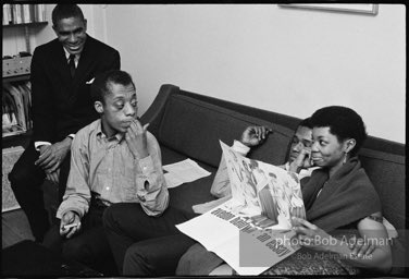 James Baldwin shows his pre-production maquette of the collaboration book with photographer Richard Avedon.(L to R) Drama coach Luther James, James Baldwin, Wayne Grice, Pearl Reynolds. At a cast party for Baldwin's play 'Blues for Mr. Charlie