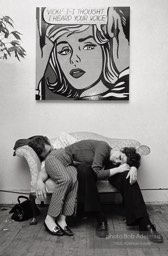 Two party-goers rest beneath a painting by Roy Lichtenstein at Robert Rauschenberg's loft studio. New York City, 1966.