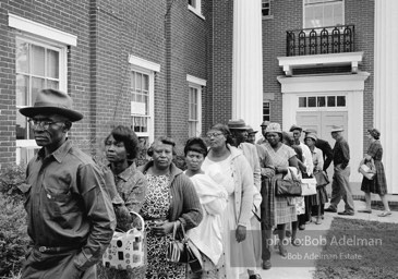 A new day dawns: Voters, most of them about to fill out their first-ever ballots, line up at the courthouse,  Camden, Alabama. 1966-

“The Voting Rights Act of 1965 changed everything, outlawing literacy tests and other barriers. It made it possible for thousands of black officials to eventually be elected in the South, and it certainly helped in
the election of two white southerners to the presidency. It was a large
factor in the gradual decrease of racial tension throughout the South. In a rare show of unity, more than forty years after the Voting Rights Act was passed, Congress renewed the measure unanimously.”