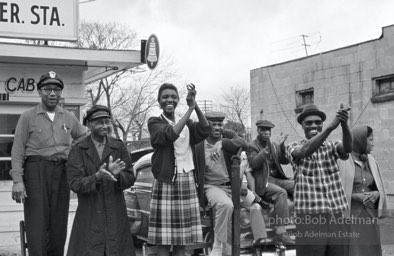The marchers are cheered by workers at a cab stand that was one of the bulwarks of the Montgomery bus boycott ten years earlier, Montgomery, Alabama. 1965