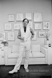 Tom Wolfe in his New York City apartment on the Upper East Side in front of a wall of his drawings.